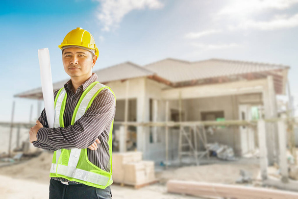 Porträt eines asiatischen Geschäftsmannes Bauingenieur Arbeiter mit Schutzhelm und Blaupausen Papier auf der Hand auf der Baustelle Hintergrund - Foto, Bild