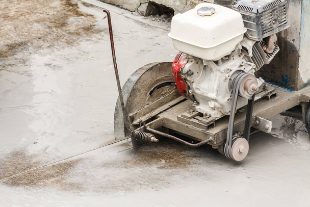 Travailleur utilisant une lame de scie diamantée coupant la route en béton sur le chantier - Photo, image