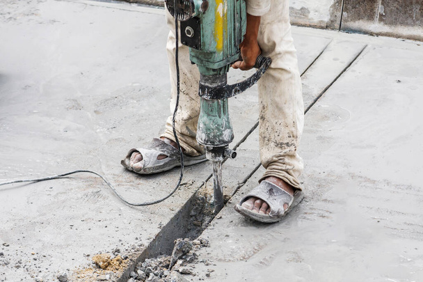 ジャックハンマー掘削コンクリート表面を使用した建設労働者 - 写真・画像