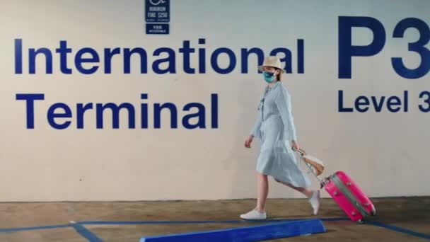 Movimento lento da mulher andando com sinalização terminal internacional em segundo plano - Filmagem, Vídeo