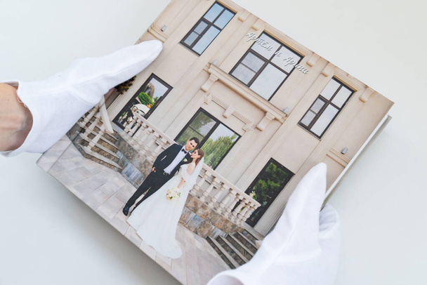 hands in white gloves holding a photo book with wedding photos.  - Fotoğraf, Görsel