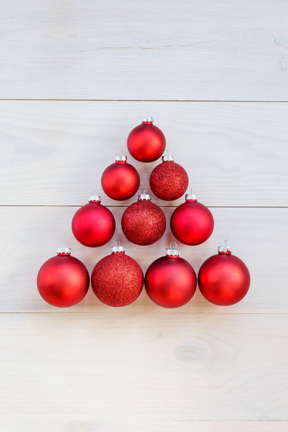 Christmas tree made of red Christmas balls on a wooden background. - Photo, Image