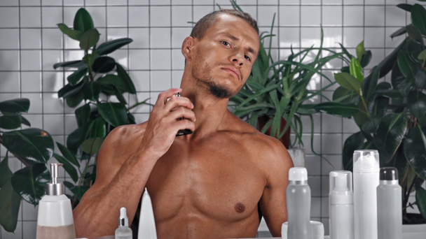 Hombre mirando a la cámara y usando perfume en el baño - Imágenes, Vídeo