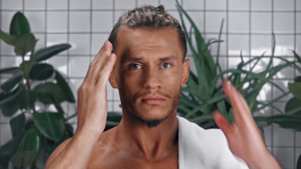 Portrait of man with towel touching hair in bathroom - Filmmaterial, Video