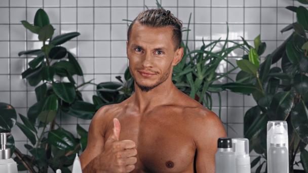 Homme regardant la caméra, pointant du doigt et montrant pouce dans la salle de bain - Séquence, vidéo