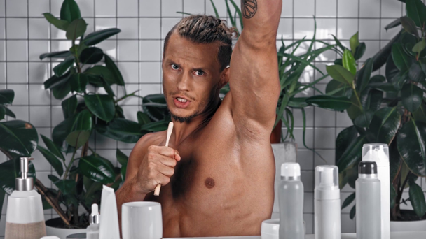 Vista frontal del hombre imitando el canto con cepillo de dientes en el baño - Imágenes, Vídeo
