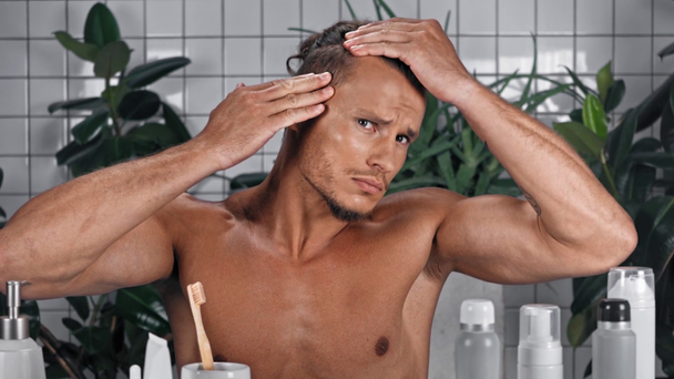 Adam kameraya bakıyor ve banyoda saçlara dokunuyor. - Video, Çekim