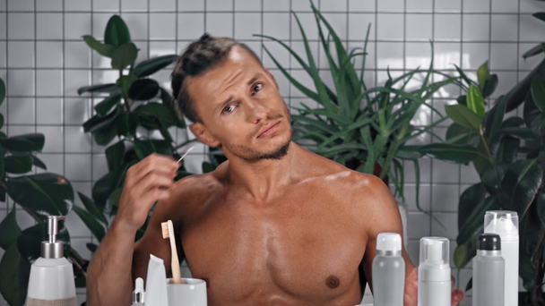 Mężczyzna używający pałeczki do uszu w łazience - Materiał filmowy, wideo