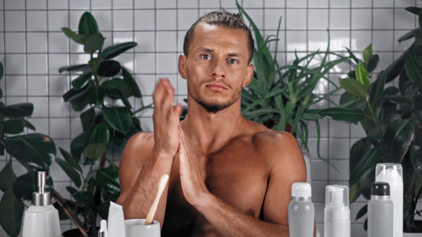 Mężczyzna ściskający mydło w płynie i pocierający nim między dłońmi w łazience - Materiał filmowy, wideo