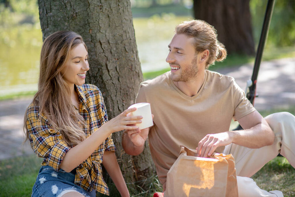 Young couple resting in the park and having lunch together - Photo, Image