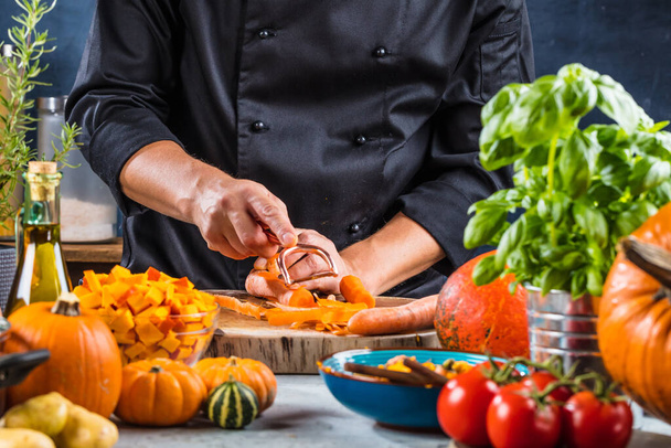 partial view of chef peeling carrots for pumpkin soup - Foto, imagen