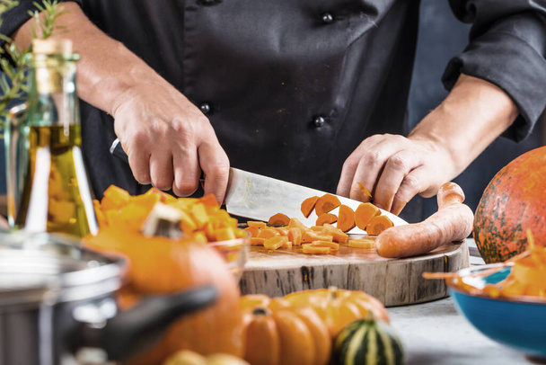 partial view of chef chopping carrots for pumpkin soup - Fotó, kép