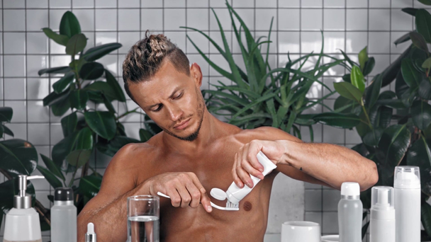 Homme serrant le dentifrice et brossant les dents dans la salle de bain - Séquence, vidéo