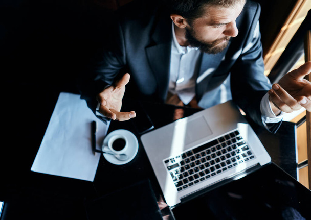 Homem de negócios sentado em um café na frente de um laptop documentos copo de café executivo vista superior tecnologia estilo de vida - Foto, Imagem