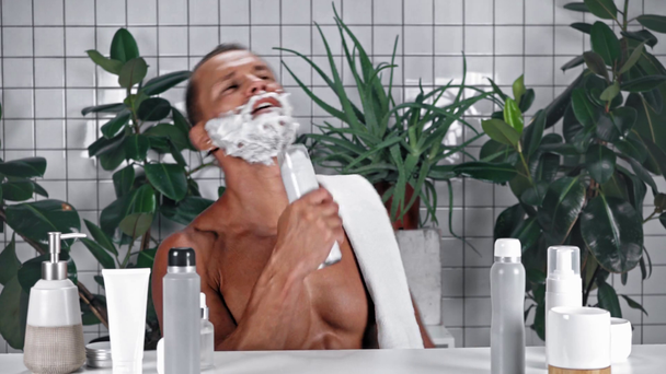 Hombre con espuma de afeitar en la cara cantando en el baño - Metraje, vídeo