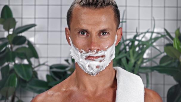 Hombre con espuma de afeitar en la cara mirando a la cámara - Metraje, vídeo