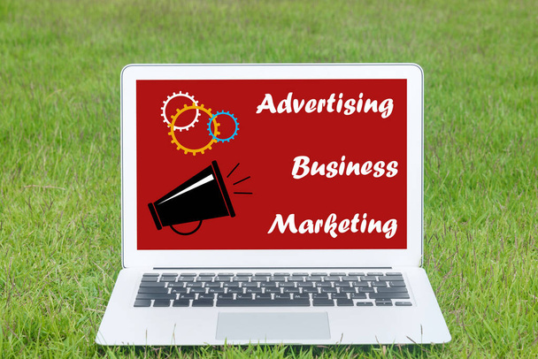 Ideas publicitarias en línea Publicidad, negocios y mensajes de marketing en la pantalla del ordenador portátil colocados en el césped. - Foto, imagen
