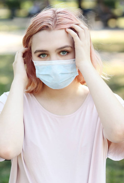 Retrato de cerca de una hermosa joven que se cubre la cara con máscara médica azul, protección contra brotes de enfermedades infecciosas pandémicas COVID-19. Concepto sanitario. - Foto, Imagen
