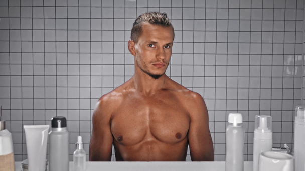 Homme regardant la caméra et debout avec les mains sur les hanches pose dans la salle de bain - Séquence, vidéo