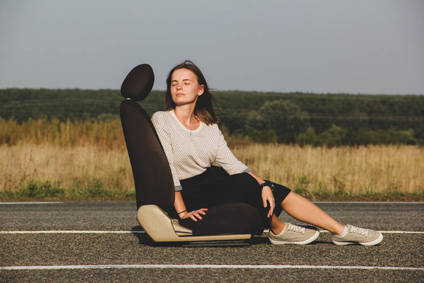 A woman sits on the road against the background of a field and sky - Photo, image
