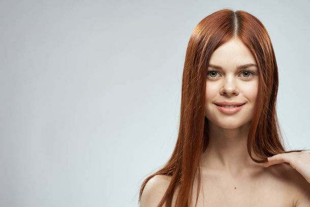 beautiful red-haired woman naked shoulders cosmetics long hair glamor light background - Photo, Image