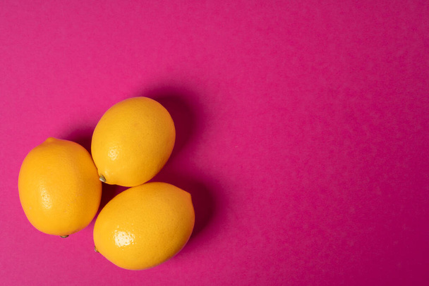 Ripe lemons on bright pink paper background - Foto, Imagem