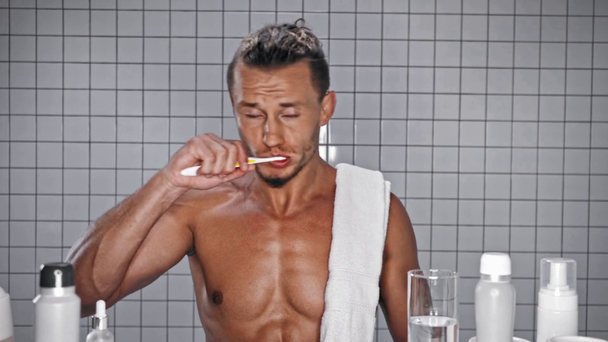 Vista frontal del hombre apretando la pasta de dientes y cepillándose los dientes  - Imágenes, Vídeo