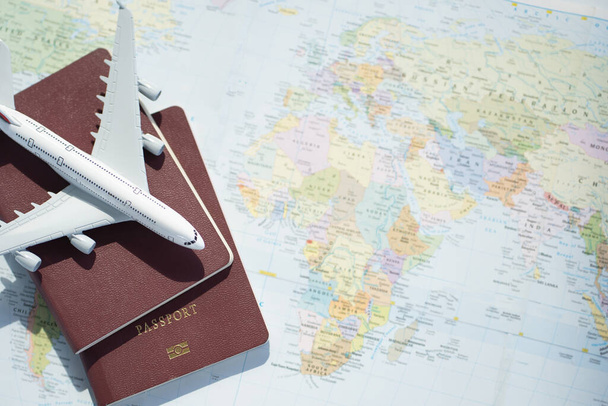 Reisepass mit Kartenhintergrund.Reiseplanung.Ansicht von Reisezubehör mit Flugzeug auf Weltkarte. Reisevorbereitung. Reisereisekonzept. - Foto, Bild