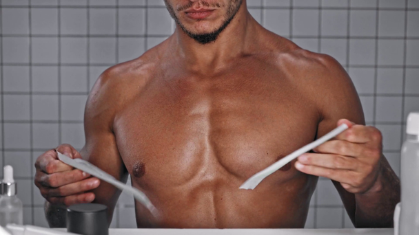 Vista cortada do homem dividindo a faixa de depilação e aplicando-a no peito  - Filmagem, Vídeo