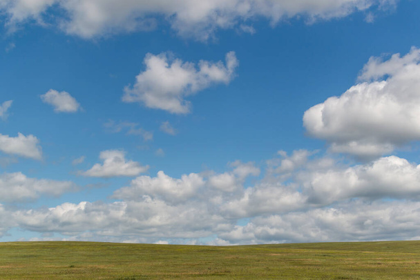 bright white fluffy clouds in blue sky with green field, open space - Foto, afbeelding
