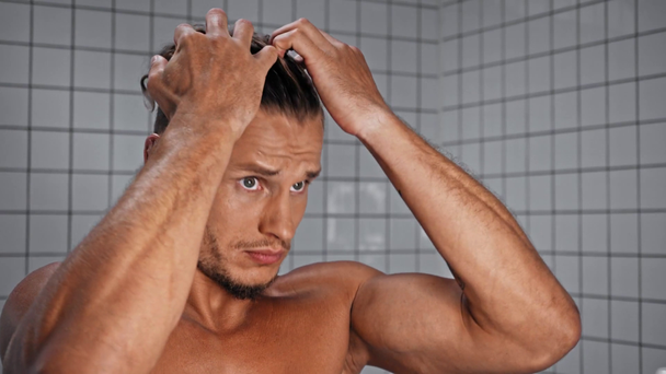 Ο άνθρωπος αγγίζει τα μαλλιά στο μπάνιο στο σπίτι - Πλάνα, βίντεο