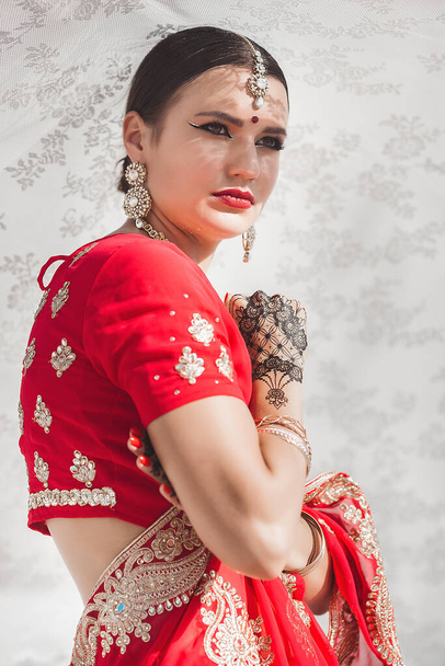 Hermosa mujer india en un fondo neutral. Dama en sari con patrón mehendi - Foto, Imagen