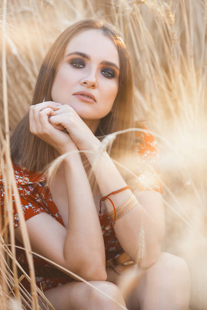 Attractive young lady in the field. Fashion girl in the wheat field - Foto, afbeelding