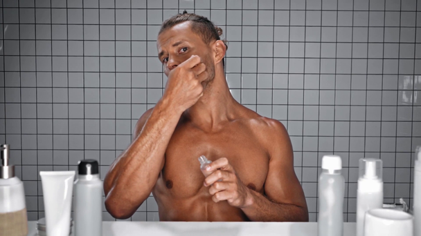 Man applying drops of serum on beard in bathroom - Séquence, vidéo