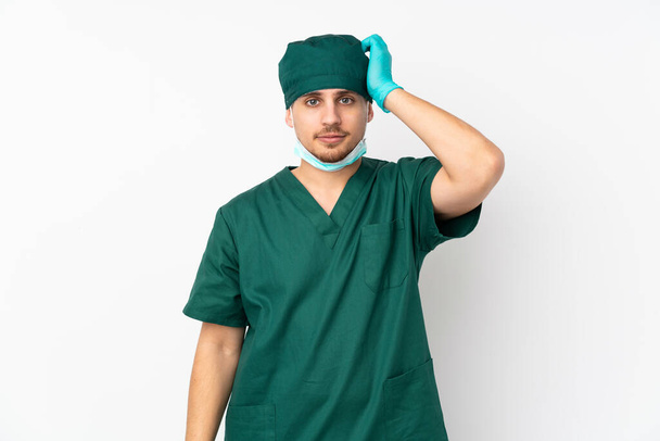 Χειρούργος με πράσινη στολή απομονωμένος σε απομονωμένο λευκό φόντο με έκφραση απογοήτευσης και μη κατανόησης - Φωτογραφία, εικόνα