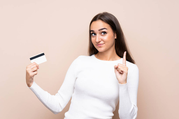 Young woman over isolated background holding a credit card - Foto, imagen