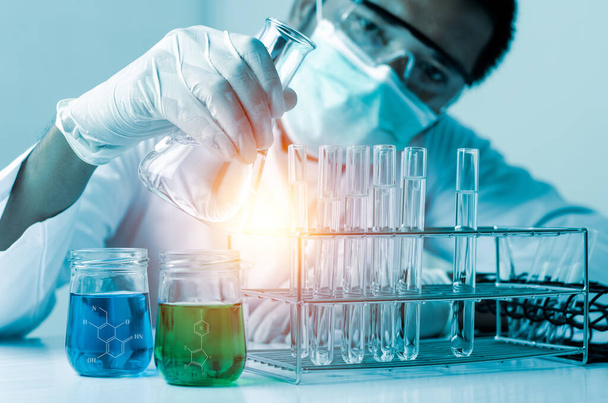 Wetenschapper hand holding fles gieten van een monster in een reageerbuis en wetenschap experimenten, Laboratorium glaswerk met chemische vloeistof,  - Foto, afbeelding