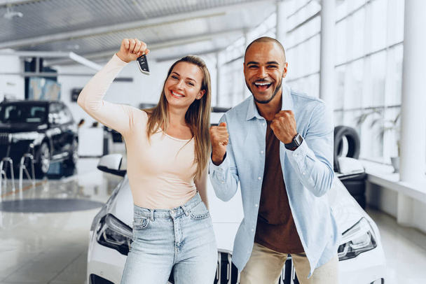 Happy excited couple buying a new car and showing keys - Zdjęcie, obraz
