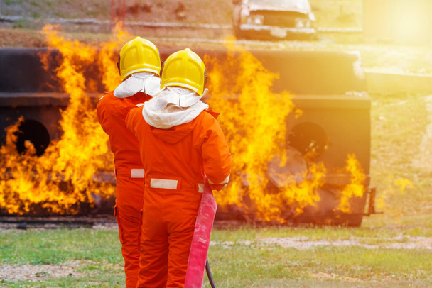 Yangın söndürücü ve hortumla yangın söndürücü kullanan iki cesur itfaiyeci ateş etmek için yüksek basınçlı su sıkan itfaiyeci tehlikeli alevlerle eğitimli itfaiyeci uzay görüntüsünü kopyalayın. - Fotoğraf, Görsel