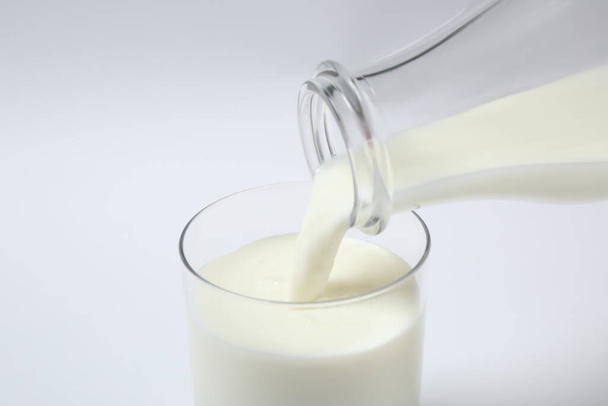 Pouring milk into glass on white background, closeup - Foto, afbeelding