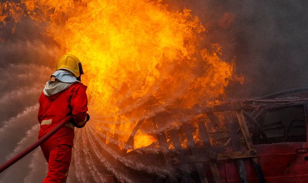 消火器と消火ホースからの水を使用して勇敢な消防士、火災に高圧水を噴霧消防士、危険な炎で消防訓練、スペースをコピー-イメージ - 写真・画像