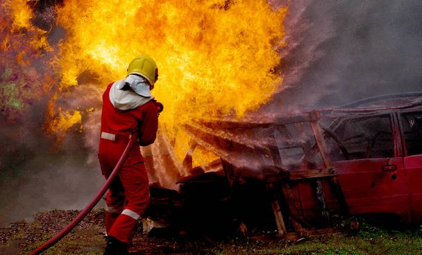 Brave brandweerman met brandblusser en water uit slang voor brandbestrijding, Brandweerman die hogedrukwater spuit om te vuren, Brandweertraining met gevaarlijke vlammen, Kopieer ruimte-Afbeelding - Foto, afbeelding