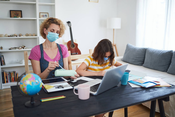 Child home studying education, homeschooling, with private tutor / mother with protective mask in the time of viruses, flu and seasonal pandemic. - Photo, Image