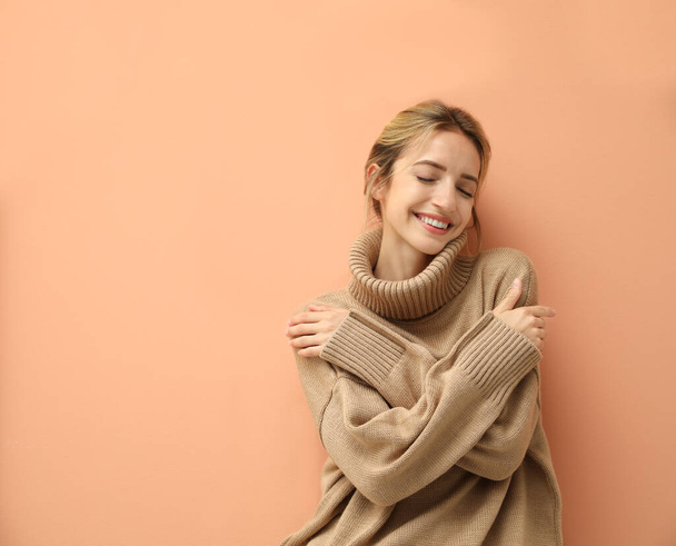 Beautiful young woman wearing knitted sweater on light brown background. Space for text - Fotó, kép