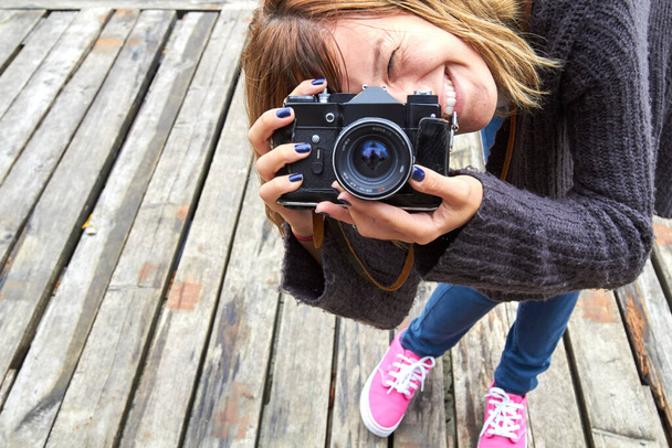 Молода біла жінка тримає старовинну ретро-камеру на відкритому повітрі
. - Фото, зображення