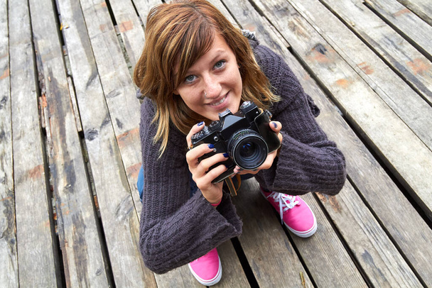 Jeune femme caucasienne tenant vintage caméra rétro en plein air. - Photo, image