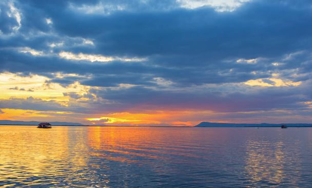 Uitzicht vanuit de lucht, prachtige oranje en rode dramatische kleuren van zonsondergang en cirrus wolken boven de zee. Hemelsblauw en oranje natuurlijke samenstelling van de dageraad over de zee, Warme kleuren weerspiegelen het wateroppervlak. - Foto, afbeelding