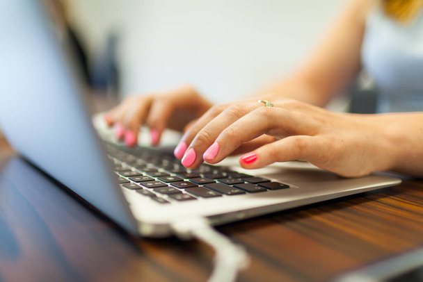 Kobieta pracująca w biurze na laptopie - zbliżenie rąk wpisujących na klawiaturze - Zdjęcie, obraz