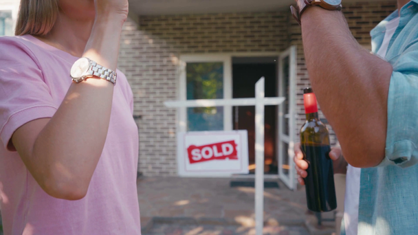 vista ritagliata di coppia clinking bicchiere di vino vicino alla nuova casa  - Filmati, video