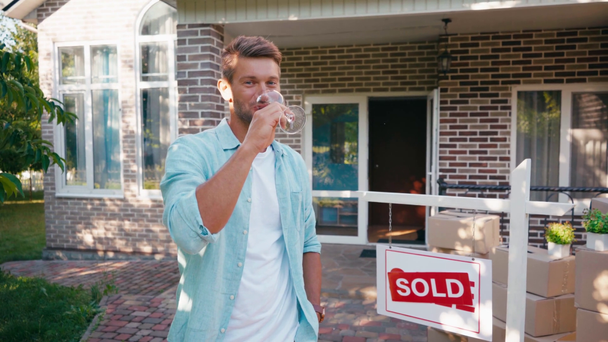 vidám ember kezében üveg és bort iszik közel az új ház - Felvétel, videó